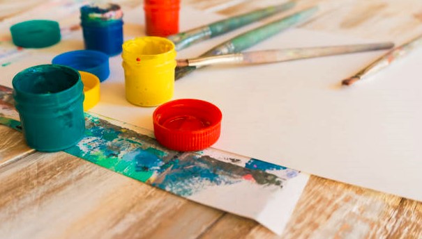 Pots of coloured paints, paint brushes and paper