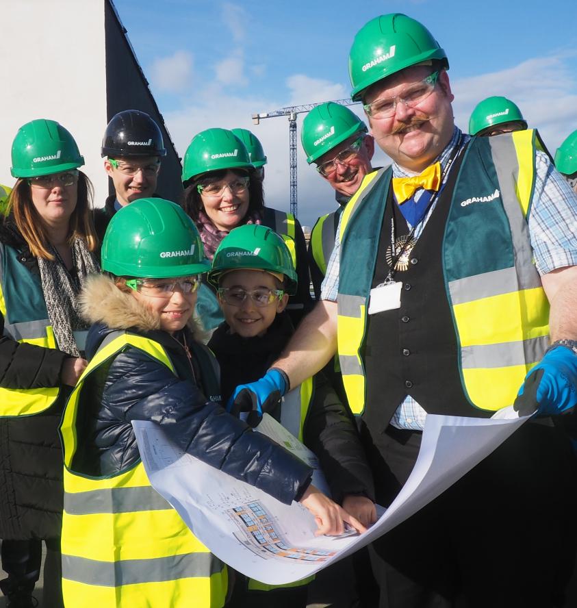 The Worshipful Mayor of Barnet, Councillor Reuben Thompstone, inspects the blueprint for the new building at its topping out ceremony