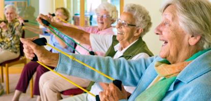Seated group of people using stretch bands to extend arms forwards